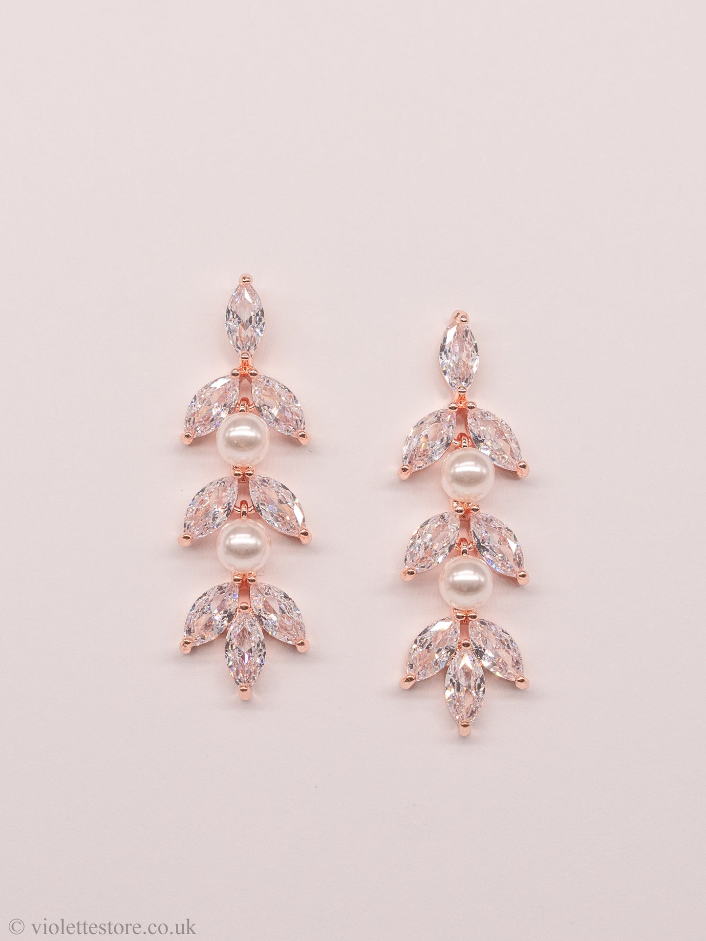 Gold & rose gold crystal earrings, a beautiful and elegant choice for both brides and bridesmaids. The style of these earrings allows them to dangle gracefully from the earlobe, catching the light and adding a touch of glamour to any wedding day look. The crystals and pearls are arranged in a beautiful design, creating a stunning visual effect.